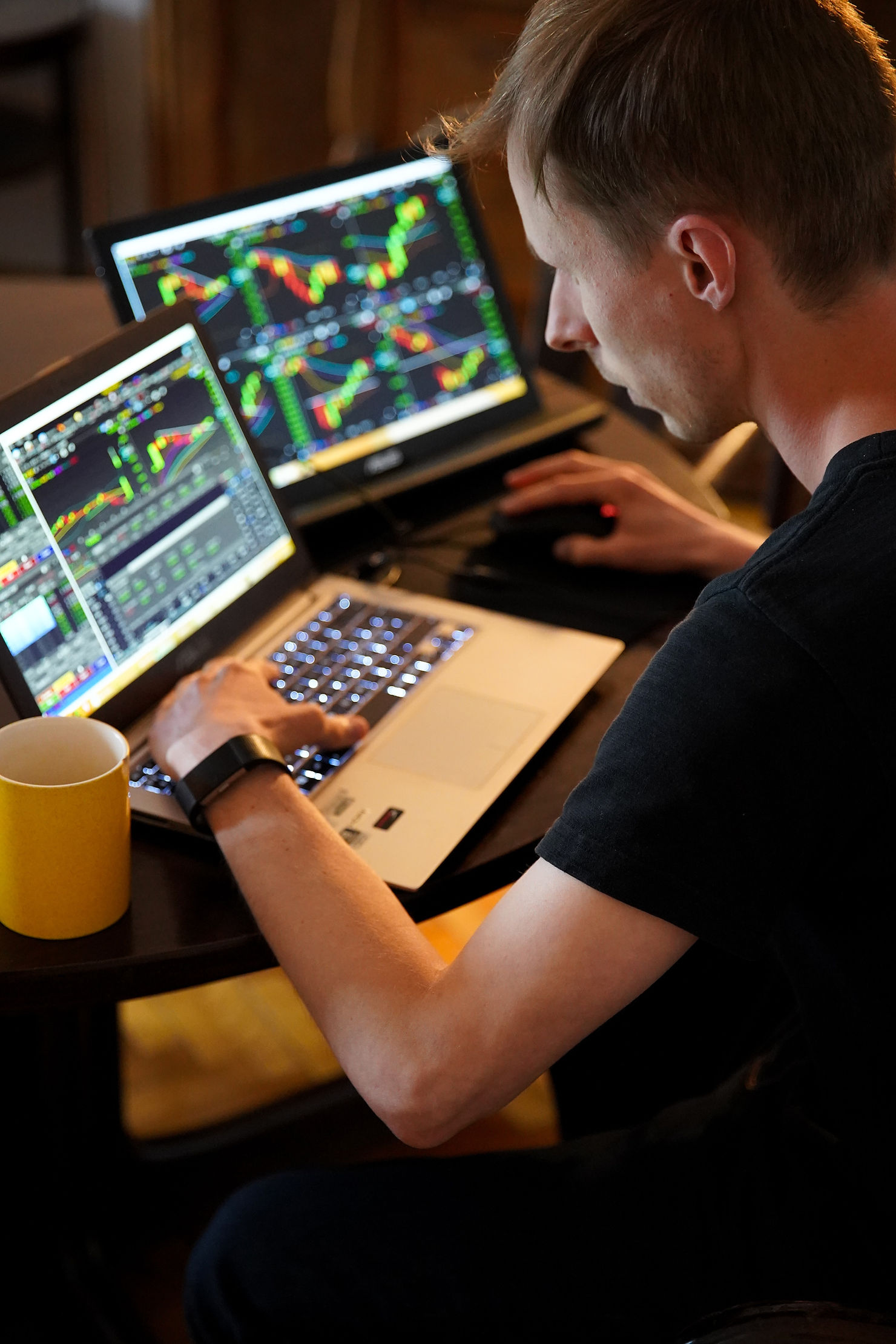 Man in front of a computer with several different charts on multiple screens.